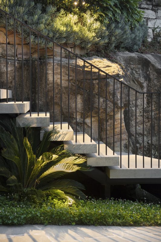 Concrete-Staircase-And-Sandstone-Rockshelf-Softened-With-Lush-Landscaping